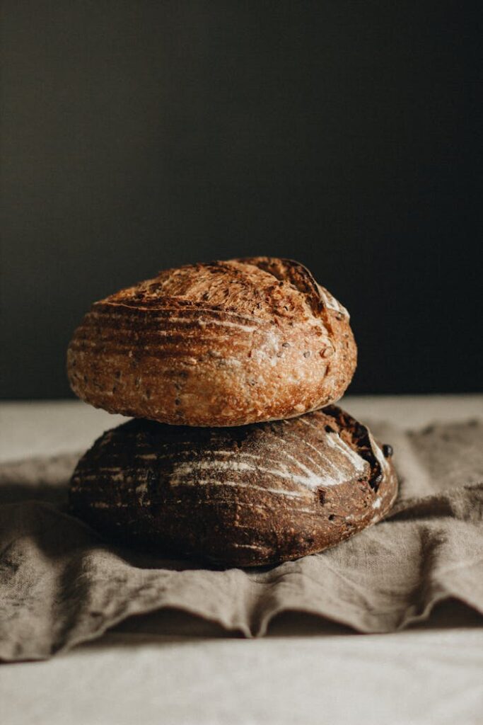 Freshly baked artisan sourdough loaves stacked on a rustic table setting.